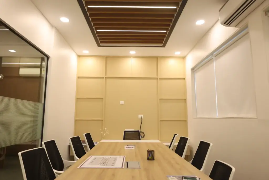 Symmetrical view of conference room with long oak table, panelled end wall and roller blind, Vora Skyline